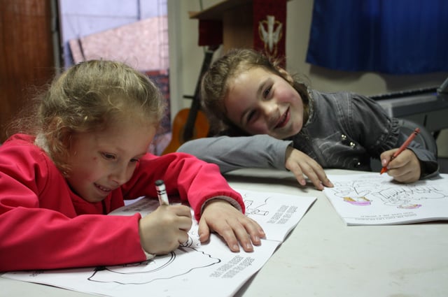Two girls enjoy putting the church's new coloring books to use.