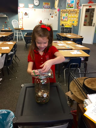 A Salem student changing the world by adding her change to her class's jar.